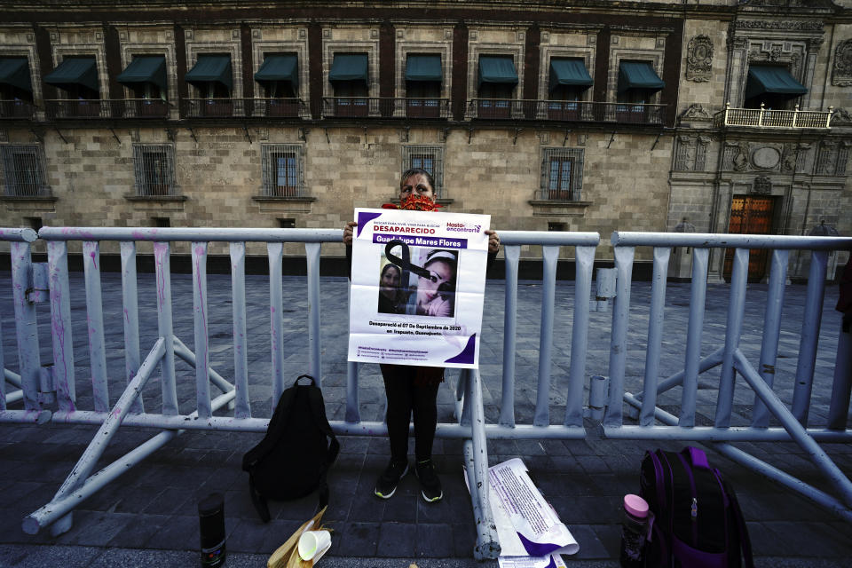 Maria de la Luz Flores holds a sign about her daughter Guadalupe Morales Flores, who she said disappeared on Sept. 7, 2020 before her body was found on March 29, 2021, during a protest outside the National Palace demanding answers from the government about people who go missing, in Mexico City, Monday, Dec. 13, 2021. (AP Photo/Marco Ugarte)