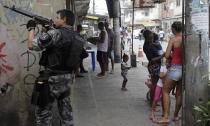 A police officer takes up position during an operation at the Mare slums complex in Rio de Janeiro March 25, 2014. Brazil will deploy federal troops to Rio de Janeiro to help quell a surge in violent crime following attacks by drug traffickers on police posts in three slums on the north side of the city, government officials said on Friday. Less than three months before Rio welcomes tens of thousands of foreign soccer fans for the World Cup, the attacks cast new doubts on government efforts to expel gangs from slums using a strong police presence. The city will host the Olympics in 2016. REUTERS/Ricardo Moraes (BRAZIL - Tags: CRIME LAW TPX IMAGES OF THE DAY)