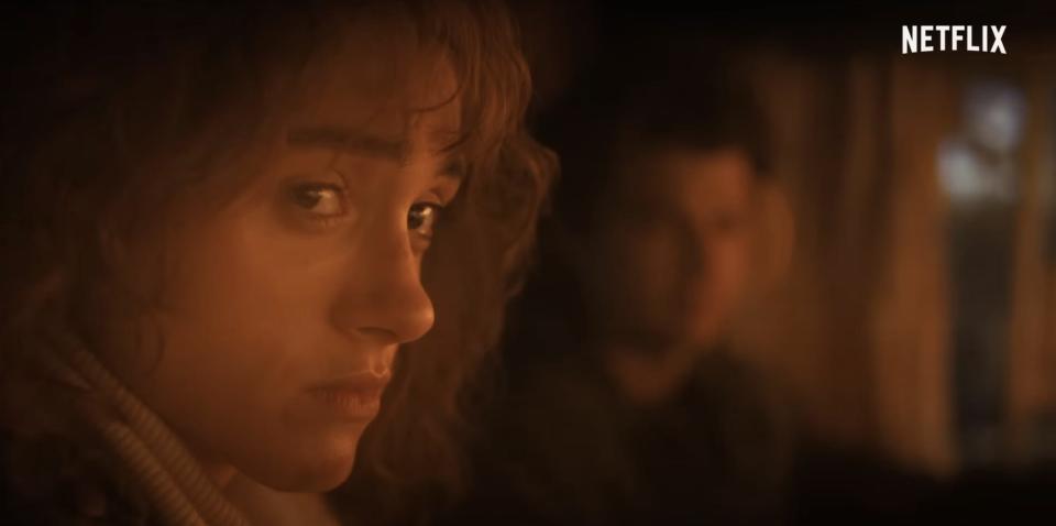 A close up of Nancy (a young woman with curly brown hair) looking distraught.