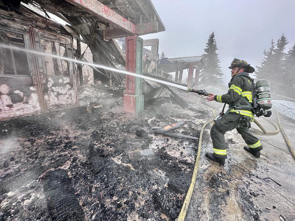 FILE PHOTO - A firefighter works at the Hurricane Ridge Day Lodge following a fire in May.