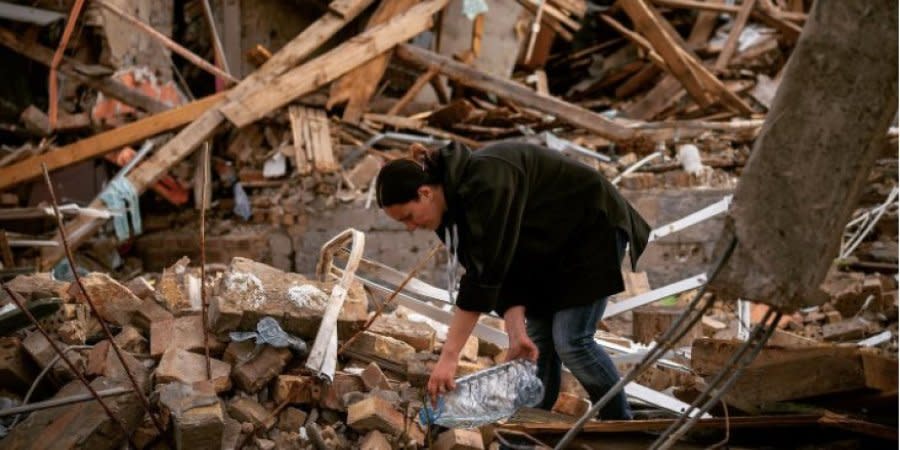 Anna Shevchenko waters her flowers in the ruins of a house in Irpin