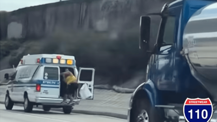 A person is seen hanging out of an ambulance on a Los Angeles freeway in an image taken from video provided by ONEHOODATATIME_MICKDOGG88 via Instagram.