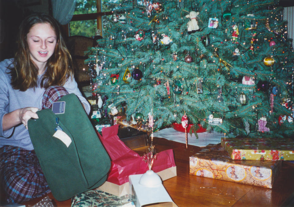 A teen is opening Christmas gifts