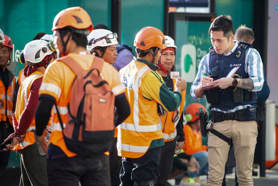 Police interview construction workers in the central business district following a shooting in Auckland, New Zealand, Thursday, July 20, 2023.