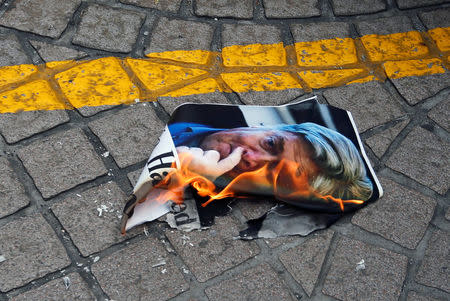 A protester burns a photo of Trump's former chief strategist Steve Bannon, before he speaks at the CLSA investor conference in Hong Kong, China September 12, 2017. REUTERS/Bobby Yip