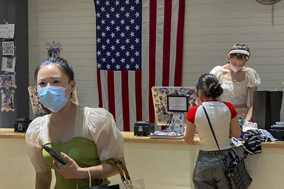 A woman wearing a face mask visits a fashion boutique in Beijing, Sunday, July 11, 2021. China on Sunday said it will take "necessary measures" to respond to the U.S. blacklisting of Chinese companies over their alleged role in abuses of Uyghur people and other Muslim ethnic minorities. (AP Photo/Andy Wong)