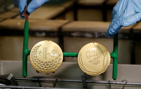 A worker from the Casa da Moeda do Brasil (Brazilian Mint) takes out gold-plated Rio 2016 Olympic and Paralympic medals in Rio de Janeiro, Brazil, June 28, 2016. REUTERS/Sergio Moraes
