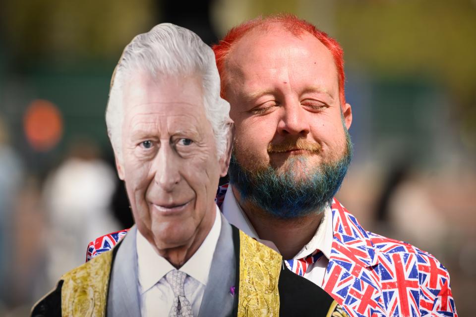A man wearing a Union Flag suit stands with a cardboard cut-out of King Charles III as he waits on the planned route of the Coronation procession (Getty Images)