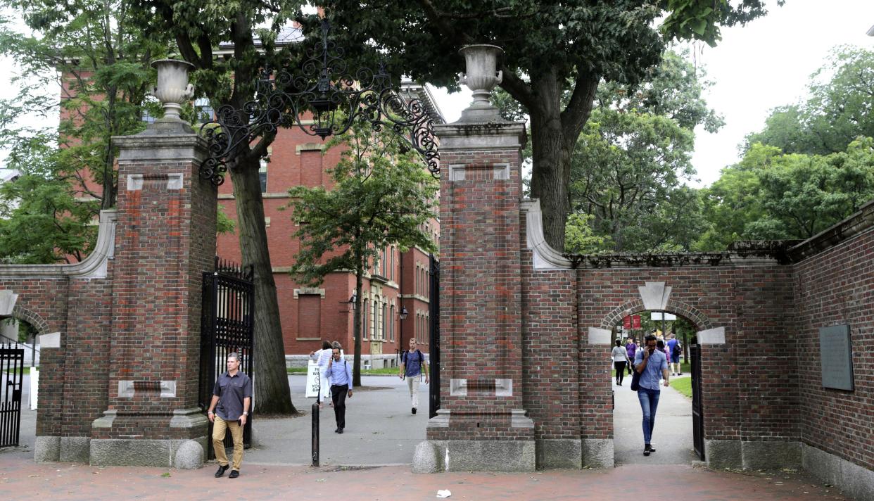 FILE - In this Aug. 13, 2019, file photo, pedestrians walk through the gates of Harvard Yard at Harvard University in Cambridge, Mass. Harvard and the Massachusetts Institute of Technology filed a federal lawsuit Wednesday, July 8, 2020, challenging the Trump administration's decision to bar international students from staying in the U.S. if they take classes entirely online this fall. Some institutions, including Harvard, have announced that all instruction will be offered remotely in the fall during the ongoing coronavirus pandemic.