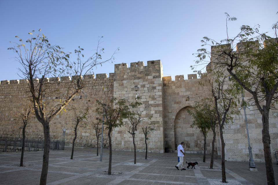 A Palestinian man walks with his dog during a three-week nationwide lockdown to curb the spread of the coronavirus in Jerusalem's old city, Sunday, Sept. 27, 2020. (AP Photo/Ariel Schalit)