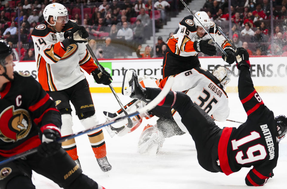 Ottawa Senators right wing Drake Batherson (19) flies through the air after clipping Anaheim Ducks goaltender John Gibson (36), who is hit by Ducks defenseman Ilya Lyubushkin (46) during the second period of an NHL hockey game Thursday, Feb. 15, 2024, in Ottawa, Ontario. (Sean Kilpatrick/The Canadian Press via AP)