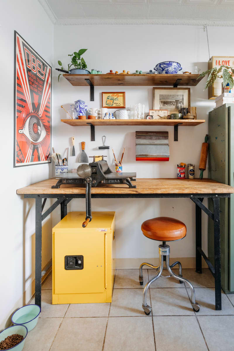 Corner view of wooden work table and wall shelves.