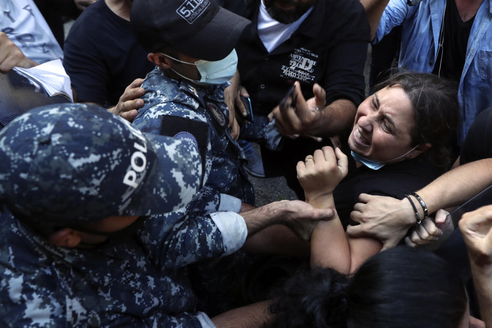 A relative of people who were killed in last year's massive blast at Beirut's seaport, scuffles with riot police as she tries to storm the home of caretaker Interior Minister Mohamed Fehmi, in Beirut, Lebanon, Tuesday, July 13, 2021. Family members are angry with Fehmi because he rejected a request by the judge investigating the explosion to question Maj. Gen. Abbas Ibrahim, who is one of Lebanon's most prominent generals and heads of the General Security Directorate. (AP Photo/Bilal Hussein)