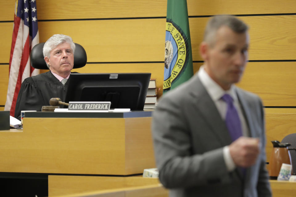 Judge Stanley Rumbaugh, left, listens as Ted Buck, right, an attorney for Chuck and Judy Cox, the parents of missing Utah woman Susan Cox Powell and the grandparents of Susan's sons Charlie and Braden, who were attacked and killed by their father Josh Powell in 2012 while he was under suspicion for Susan Powell's disappearance, makes his opening arguments, Tuesday, Feb. 18, 2020, in Pierce County Superior Court in Tacoma, Wash., on the first day of a civil lawsuit over the murder of her young sons by Josh Powell. The Coxes allege that negligence by the Washington state Department of Social and Health Services was a contributing factor that led to the deaths of their grandsons. (AP Photo/Ted S. Warren)