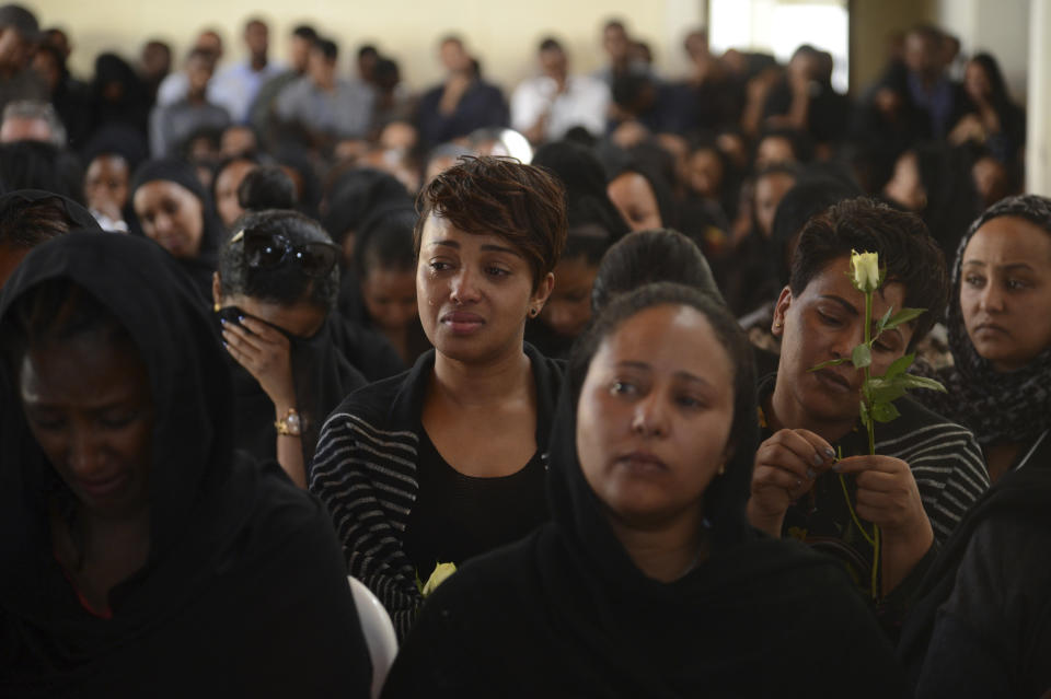 Mourners attend a memorial service held by an association of Ethiopian airline pilots, at which framed photographs of seven crew members were on display, in Addis Ababa, Ethiopia Monday, March 11, 2019. Authorities in Ethiopia, China and Indonesia grounded all Boeing 737 Max 8 aircraft Monday following the crash of an Ethiopian Airlines jetliner that killed 157 people, and investigators found the flight recorders from the field where the plane went down. (AP Photo/Samuel Habtab)