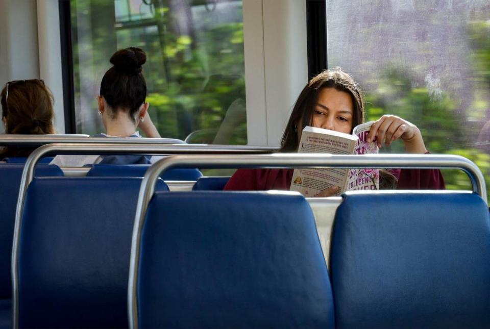Elizabeth Prats, an HR director, right, enjoys a book during her 50-minute commute from Dadeland North to the Government Center on Wednesday, July 24, 2024, in Miami. Prats said she would vote in favor expansion of transit.