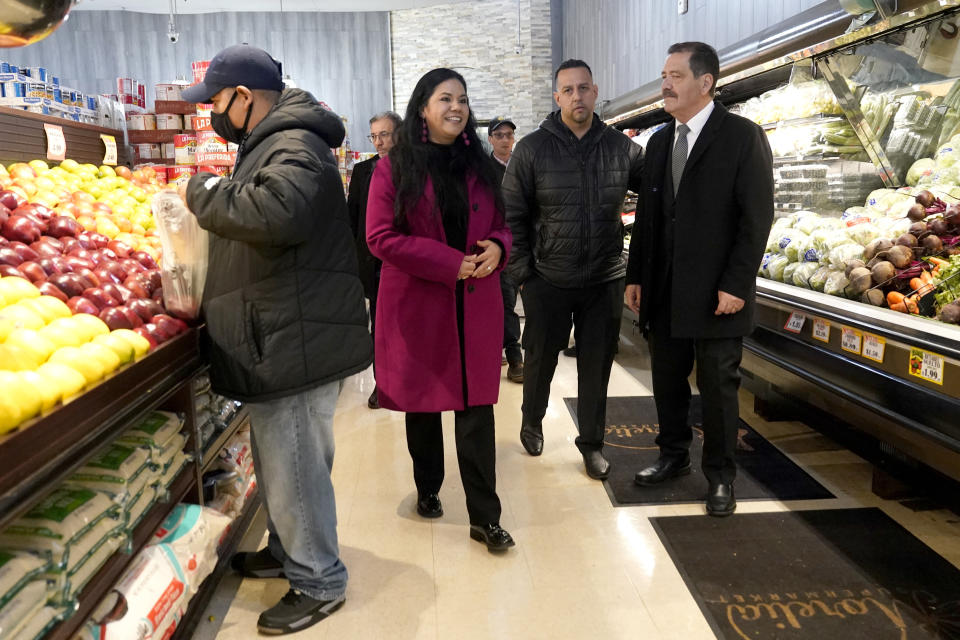 Chicago mayoral candidate Rep., Jesus "Chuy" Garcia, D-Ill., right, visits the Morelia Supermarket with Alderman Felix Cardona, center, and store manager Yucy Hernandez, as a shopper buys produce during a campaign stop Wednesday, Feb. 22, 2023, in Chicago. Garcia, who continues to seek the mayor's office, forced then-Mayor Rahm Emanuel to a runoff in 2015. (AP Photo/Charles Rex Arbogast)