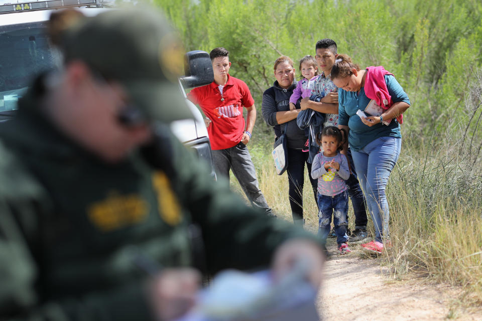 Central American migrants wait as U.S. Border Patrol agents take people into custody on June 12, 2018, near McAllen, Texas.