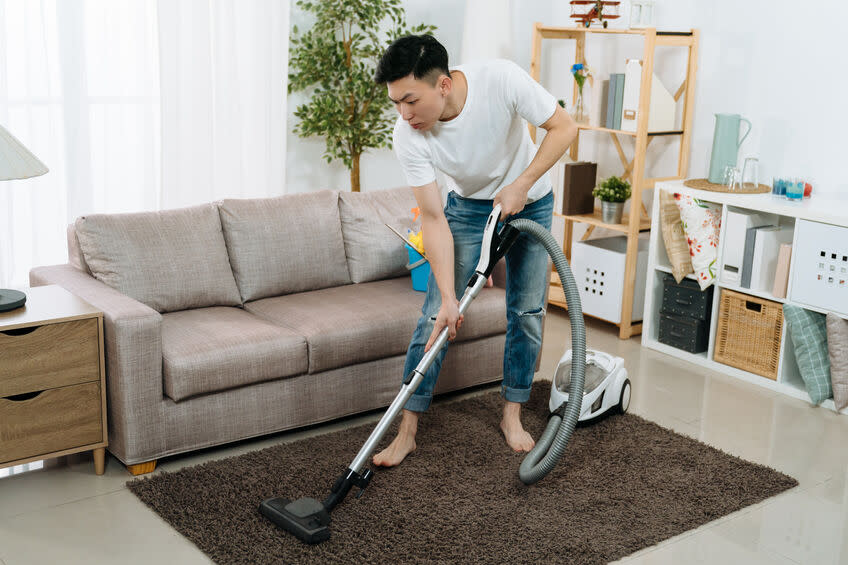 man cleaning carpet with vacuum cleaner