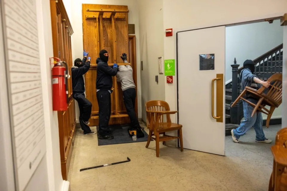 Ocupantes bloquean una puerta con una mesa dentro del edificio.