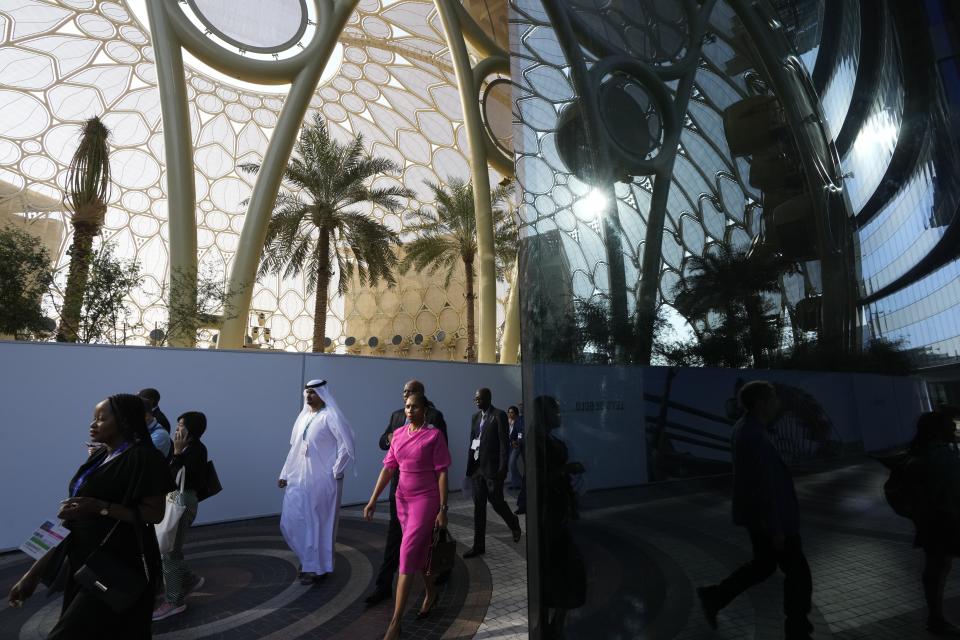 People walk through the COP28 U.N. Climate Summit near Al Wasl Dome at Expo City, Sunday, Dec. 3, 2023, in Dubai, United Arab Emirates. (AP Photo/Peter Dejong)