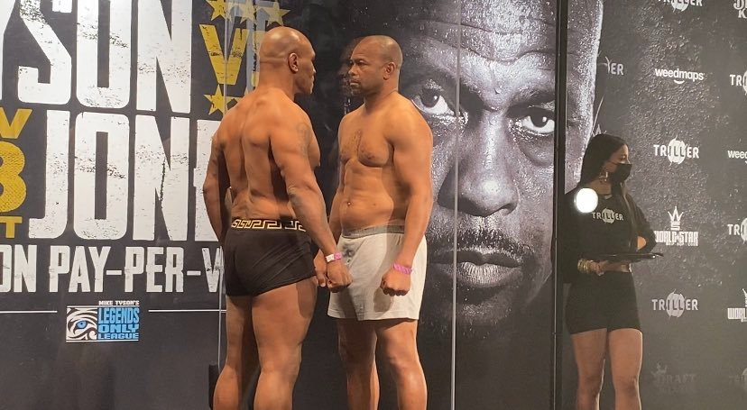 Mike Tyson, left, and Roy Jones Jr. have a stare down while separated by plexiglass after their weigh-in on Friday.