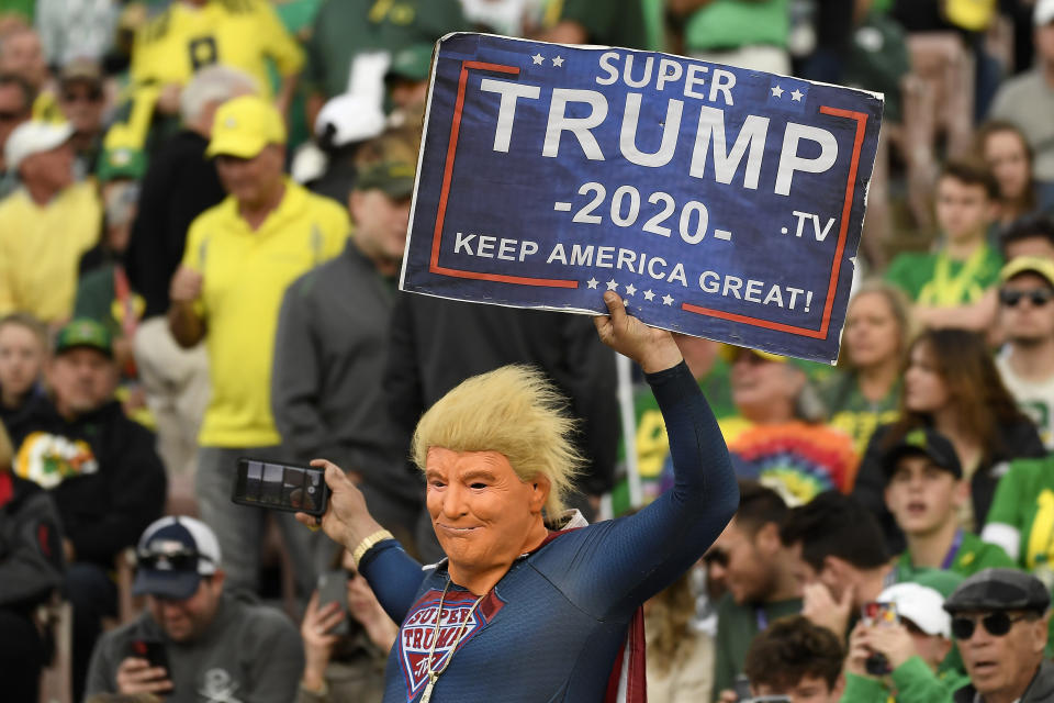 PASADENA, CALIFORNIA - JANUARY 01: A fan dressed as Super Trump holds up a sign that reads, "Super Trump 2020 Keep America Great!" during third quarter in the Rose Bowl game presented by Northwestern Mutual between the Oregon Ducks and the Wisconsin Badgers at Rose Bowl on January 01, 2020 in Pasadena, California. (Photo by Kevork Djansezian/Getty Images)