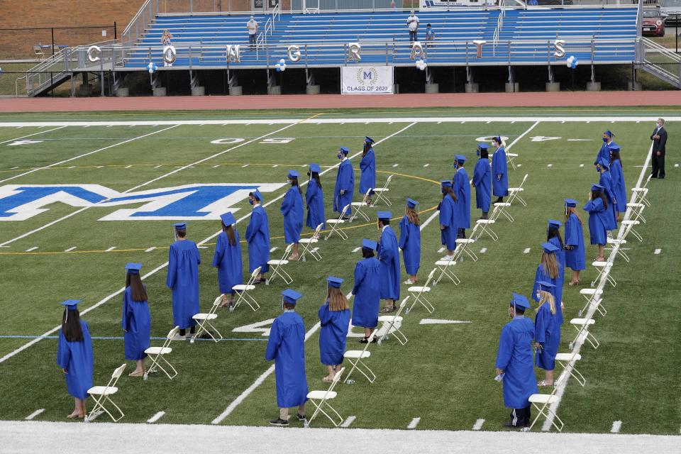 Graduating students socially distance during a graduation ceremony at Millburn High School in Millburn, N.J., Wednesday, July 8, 2020. This week New Jersey saw the resumption of youth day camps, in-person summer school and school graduation ceremonies, capped at 500 people and required to be outside. (AP Photo/Seth Wenig)