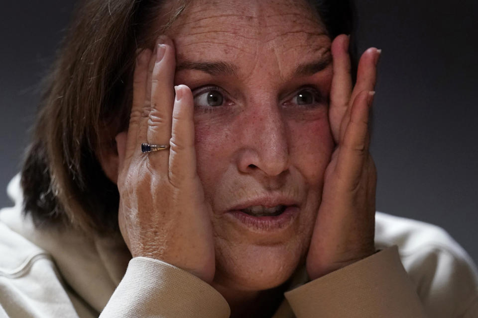 Shooting survivor Tammy Asselin clutches her face while reflecting on surviving a mass shooting by Army reservist Robert Card, during an interview, Wednesday, Dec. 27, 2023, in Lewiston, Maine. Despite the warning by Card's friend and fellow Army reservist Sean Hodgson, which came alongside a series of other glaring red flags, Army officials discounted the warnings and ultimately did not stop Card from committing Maine's deadliest mass shooting when he killed multiple people in Lewiston in October. (AP Photo/Charles Krupa)