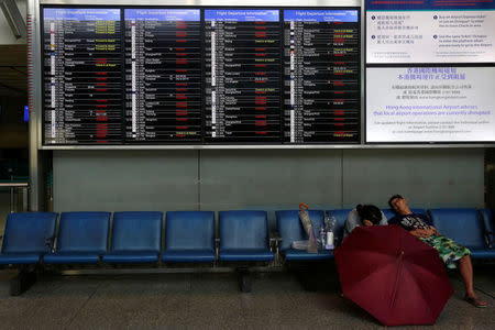 People rest underneath a panel displaying cancelled and delayed flights at a downtown check-in centre as Typhoon Haima approaches in Hong Kong, China, October 21, 2016 . REUTERS/Bobby Yip