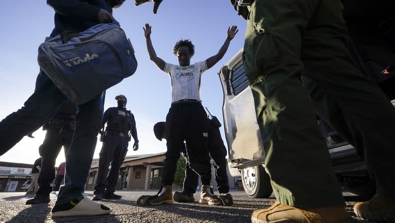 Migrant men are searched and escorted into a van by Border Patrol agents on Friday, Dec. 15, 2023, near Lukeville, Ariz.