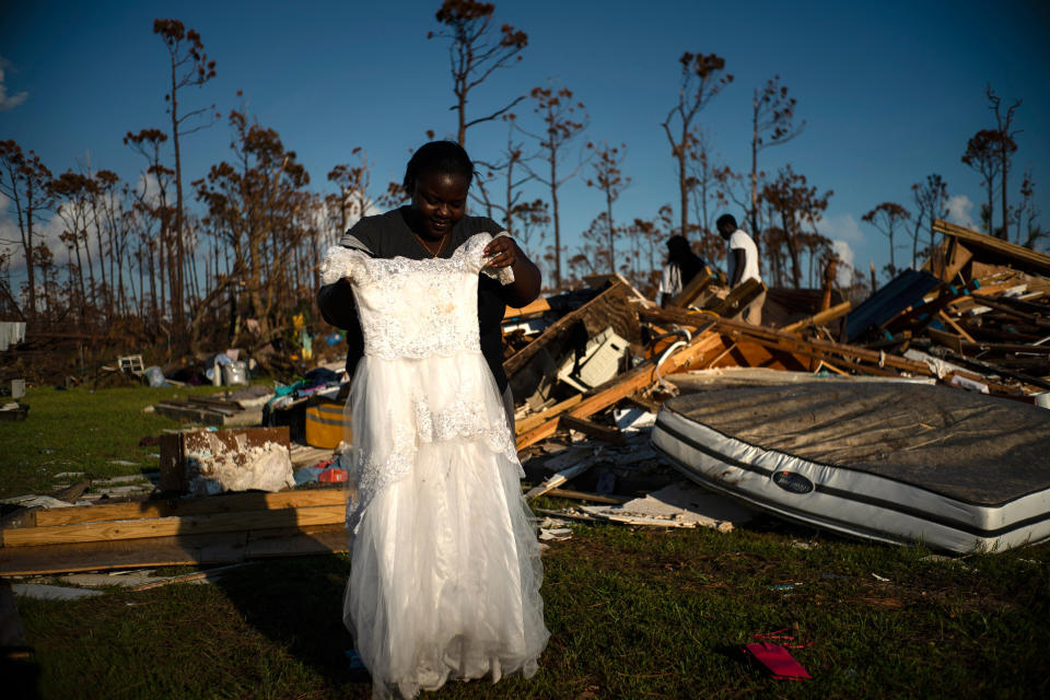 Synobia Reckley holds up the dress her niece wore as a flower girl at her wedding, as she goes through valuables in the rubble of her home destroyed one week ago by Hurricane Dorian in Rocky Creek East End, Grand Bahama, Bahamas, Sept. 8, 2019. | Ramon Espinosa—AP