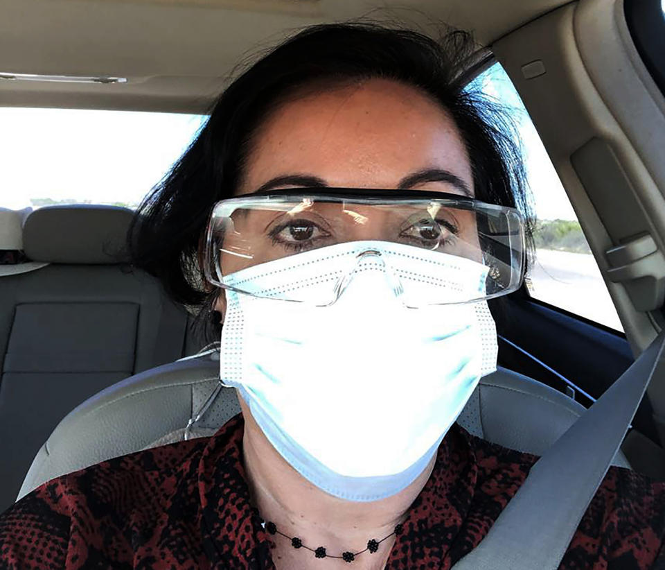 This March 23, 2020 photo provided by Margarita Silva shows her outside the La Palma Detention Center in Eloy, Ariz., wearing her husband’s land surveyor goggles, a mask she borrowed from a friend and medical gloves she got from a hardware store. Attorneys and judges in U.S. immigration courts are trying to protect themselves from the coronavirus with borrowed masks and hand sanitizer. The Trump administration has delayed hearings for immigrants who aren't in detention but is moving forward for those who are. (Margarita Silva via AP)