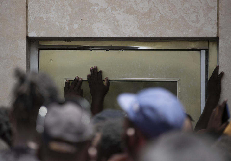 Haitians crowd around a door of the U.S. Embassy in Port-au-Prince, Haiti, Friday, July 9, 2021. A large crowd gathered outside the embassy amid rumors on radio and social media that the U.S. will be handing out exile and humanitarian visas, two days after Haitian President Jovenel Moïse was assassinated in his home. (AP Photo/Fernando Llano)