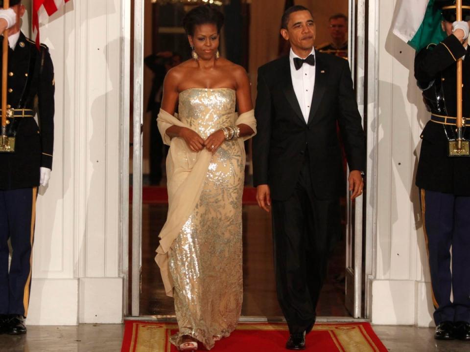 Barack and Michelle Obama at a state dinner. Michelle wears a gold sparkly dress.