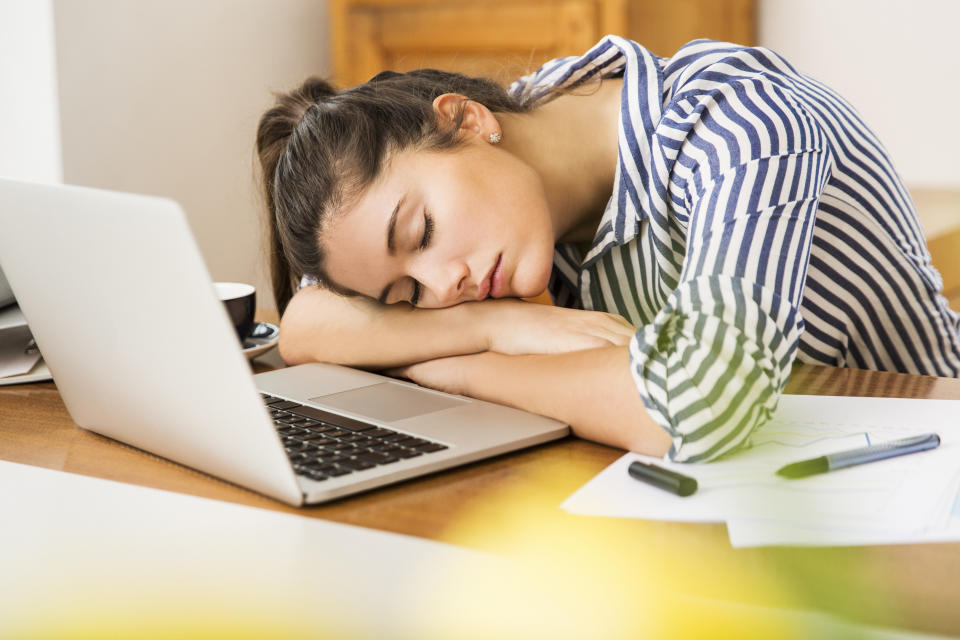 A woman naps infront of her laptop