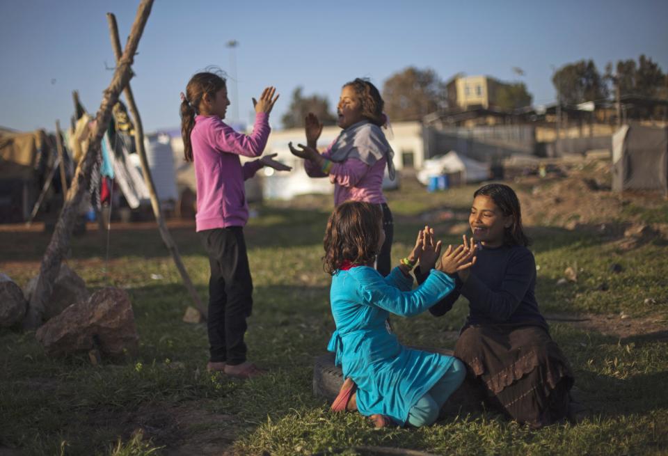 In this Friday, April 4, 2014 photo, Syrian girls play in an unofficial refugee camp on the outskirts of Amman, Jordan. Some residents, frustrated with Zaatari, the region's largest camp for Syrian refugees, set up new, informal camps on open lands, to escape tensions and get closer to possible job opportunities.(AP Photo/Khalil Hamra)