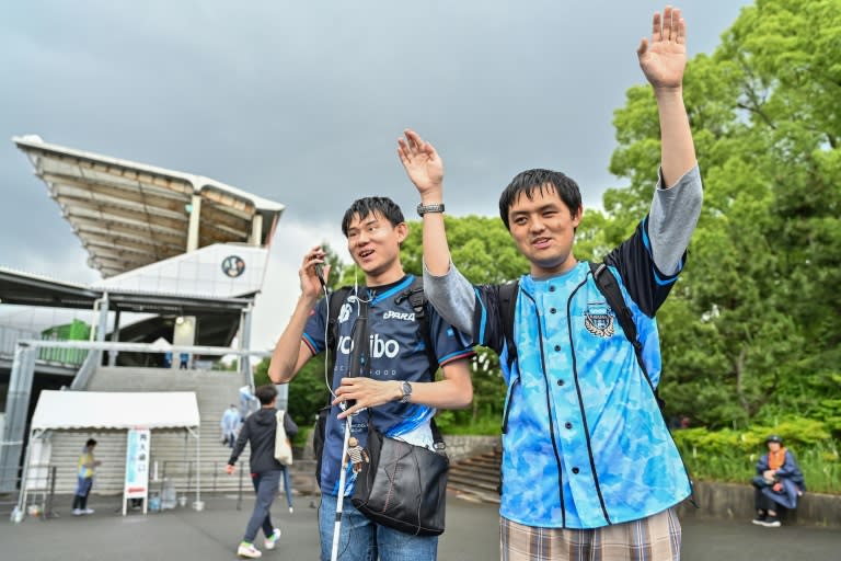 Mashiro (L) cheering with his friend after they arrive at a stadium using an app with ChatGPT for directions (Richard A. Brooks)