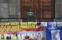 A soldier wearing a mask amid the new coronavirus pandemic watches a protest by relatives of the disappeared in front of the National Palace in Mexico City, Thursday, June 4, 2020. Relatives of different groups searching for the disappeared protested the cut to the budget destined for their search. (AP Photo/Eduardo Verdugo)