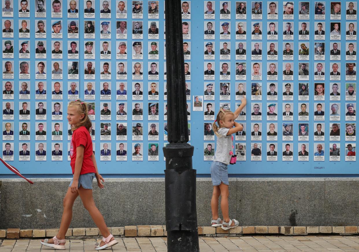 Girls play next to the memory wall of fallen defenders of the country, amid Russia's attack of Ukraine (REUTERS)