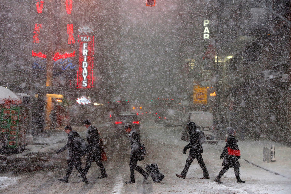 Pedestrians walk in Times Square as snow falls in Manhattan