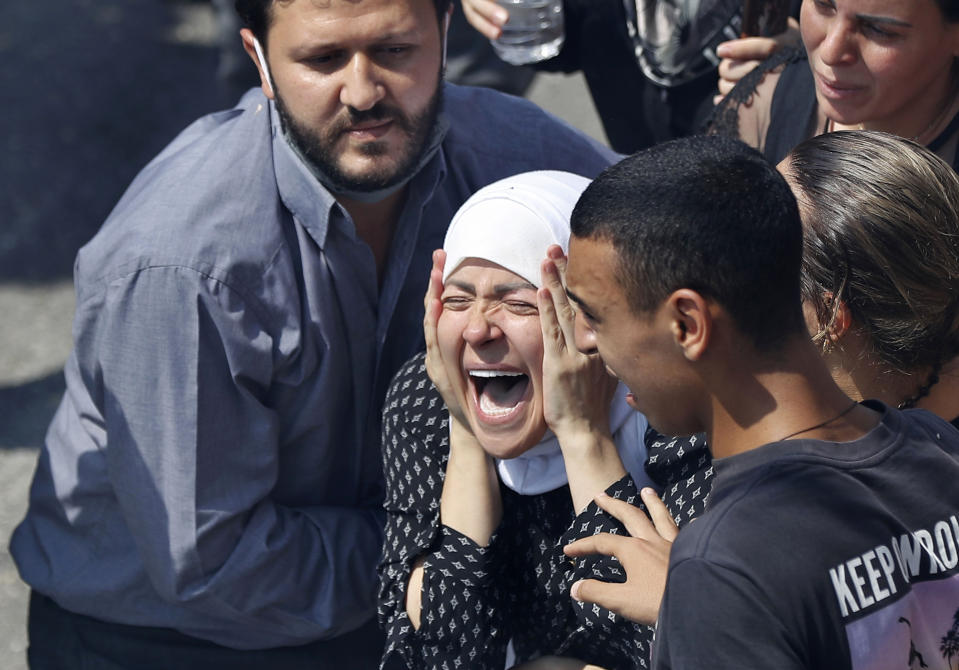 FILE - In this Tuesday, Aug. 11, 2020 file photo, the wife of Rami Kaaki, one of ten firefighters who were killed during the Aug. 4 explosion that hit the seaport of Beirut, mourns during her husband's funeral at the firefighter headquarters, in Beirut, Lebanon. It was 20 minutes before 6:08 p.m. when the Beirut fire brigade received the call from an employee at the nearby port reporting a big fire. Ten firefighters, including a female paramedic, piled into a fire engine and an ambulance and raced toward the scene, and their ultimate death. (AP Photo/Hussein Malla, File)