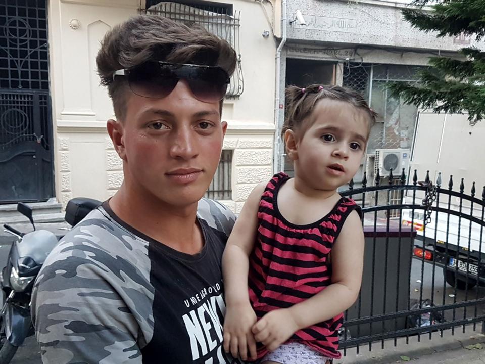 Feuzi Zabaat, 17, poses with toddler Doha Muhammed he caught as she was falling from the second floor at Fatih district in Istanbul on June 27, 2019.