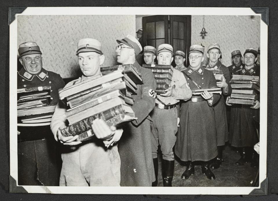 This photo released by Yad Vashem, World Holocaust Remembrance Center, shows German Nazis carrying Jewish books, presumably for burning, during Kristallnacht intake most likely in the town of Fuerth, Germany on Nov. 10, 1938. Israel’s Yad Vashem Holocaust memorial has acknowledged that a series of photos from Nazi Germany’s 1938 pogroms against Jews have been seen and published before, revising a claim it made when releasing the photos last week. They have been previously seen, on Twitter, in a research publication, and a recent PBS documentary. On Sunday, Nov. 13, 2022 Yad Vashem clarified its error in reply to a query from the AP. (Yad Vashem via AP)