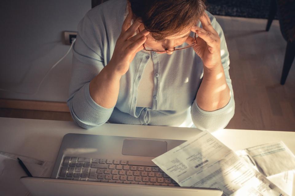 Person stressed out at computer looking at bills