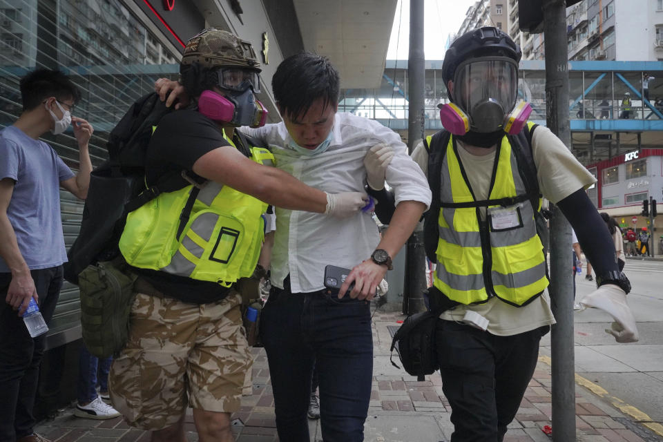 Medical volunteers help a man to move away as police fire teargas during a protest against Beijing's national security legislation in Causeway Bay in Hong Kong, Sunday, May 24, 2020. Hong Kong police fired volleys of tear gas in a popular shopping district as hundreds took to the streets Sunday to march against China's proposed tough national security legislation for the city. (AP Photo/Vincent Yu)