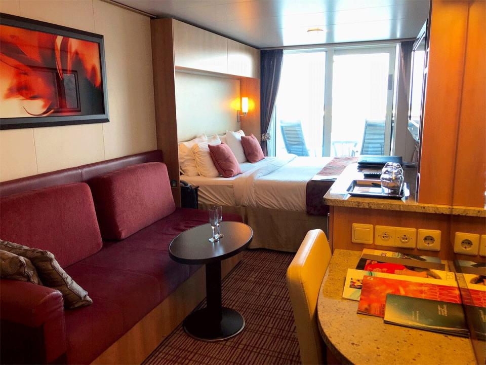 balcony stateroom on celebrity cruise with a couch, bed, and doors to a balcony overlooking the water