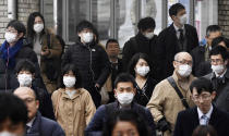 People wearing face masks walk on a street in Nara, western Japan, Wednesday, Jan. 29, 2020. Japan's health officials on Tuesday said that it has confirmed what could be the first human-to-human infection in the country. The first suspected person-to-person infection involves a male patient in his 60s from Nara, who has not traveled to Wuhan. The man, however, is a tour bus driver who served two groups of Chinese tourists from Wuhan from Jan. 8-16. (Nobuki Ito/Kyodo News via AP)