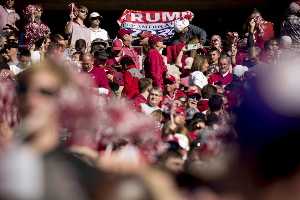 A member of the audience holds up a pro-Trump flag as President Donald Trump and first lady Melania Trump attend a NCAA college football game between LSU and Alabama at Bryant-Denny Stadium, in Tuscaloosa, Ala., Saturday, Nov. 9, 2019. (AP Photo/Andrew Harnik)