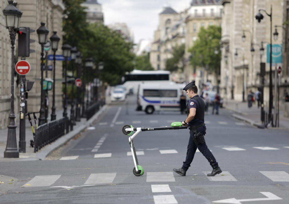 Police officers remove electric scooters from the area around Notre Dame cathedral in Paris, Monday, Aug. 12, 2019. Authorities started clearing the area around Notre Dame ahead of decontamination and cleanup work which will resume on Aug. 19 after new equipment and stricter safety procedures ensure workers are not exposed to unsafe levels of lead. (AP Photo/Lewis Joly)